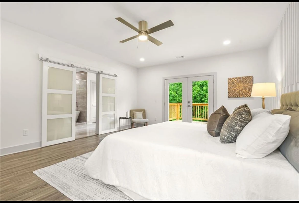 Staged owner's suite with a barn door and private deck access