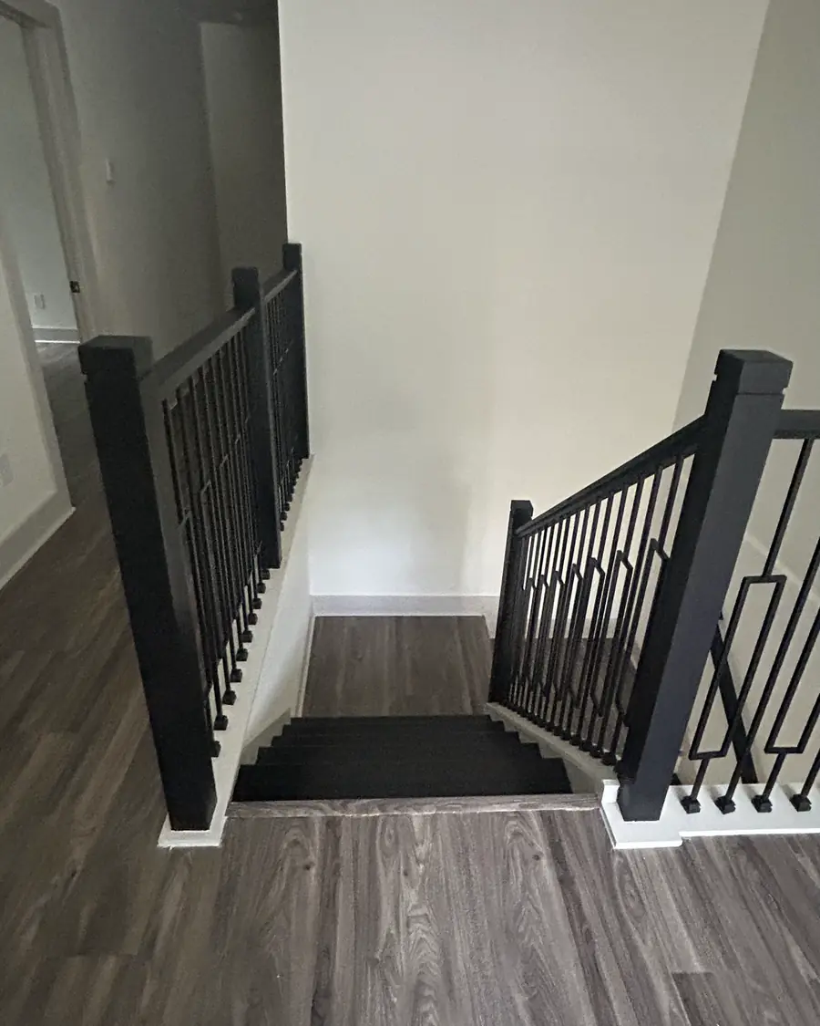 Finished staircase and upstairs landing with a black metal railing